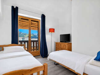 This charming bedroom features two twin beds with crisp white linens, perfect for a cozy mountain retreat.
