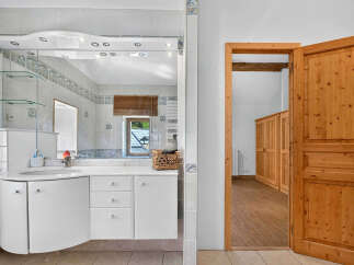 Discover this charming bathroom featuring a sleek white vanity with a curved countertop and ample storage.