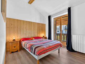 Experience cozy mountain living in this charming bedroom featuring a comfortable bed with a vibrant striped comforter.