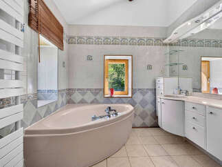 Experience tranquility in this charming bathroom featuring a luxurious corner bathtub perfect for unwinding.