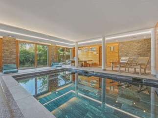 Indulge in relaxation at this indoor swimming pool featuring a tranquil ambiance and natural stone accents.