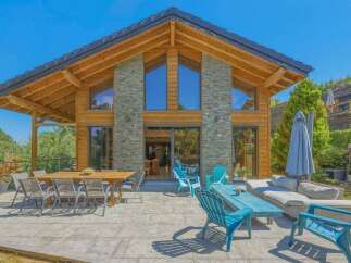 Experience luxurious mountain living in this stunning chalet, featuring a grand wooden exterior and a stone-accented facade.