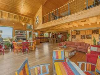 Experience rustic charm in this spacious wooden home featuring an open-concept living area with a large dining table and a cozy seating area.