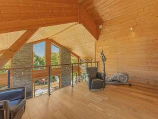 Experience luxury living in this stunning wooden-clad home featuring a spacious loft area with breathtaking views through large windows.