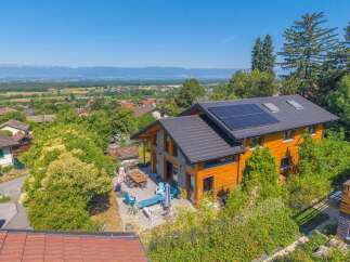 Discover this stunning modern home featuring a beautiful wooden exterior and a dark tiled roof equipped with solar panels.