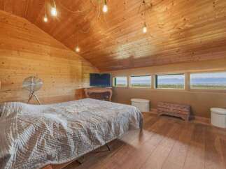 Experience breathtaking panoramic views from this charming attic bedroom, featuring a cozy bed and a vintage fan.