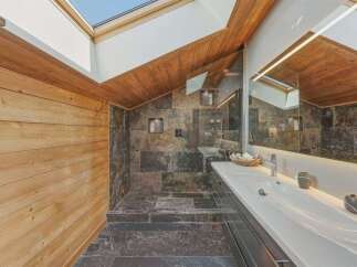 Experience rustic luxury in this stunning bathroom featuring natural wood paneling and slate tile accents.