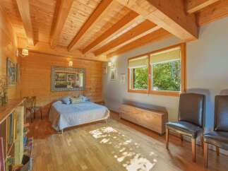 Experience rustic charm in this cozy bedroom featuring exposed wooden beams and paneling.