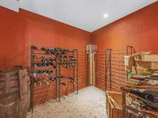 Discover this exceptional wine cellar, featuring a rustic wooden barrel and extensive metal wine racks, perfect for storing your prized collection.
