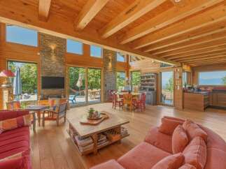 Experience luxurious mountain living in this stunning log cabin featuring a spacious open-concept living area with exposed wooden beams and a stone accent wall.