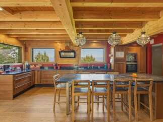 Experience rustic charm in this spacious log cabin kitchen, featuring warm wood beams, ample counter space, and a large island perfect for entertaining.