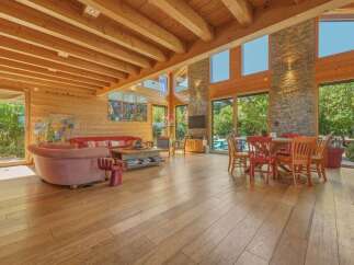 Experience luxurious living in this stunning open-concept great room, featuring a vaulted wood-beamed ceiling and expansive windows that flood the space with natural light.