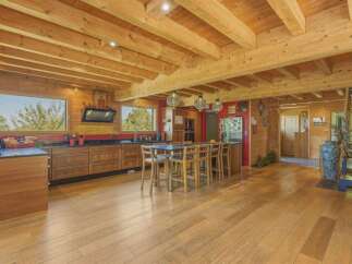 Experience rustic charm in this spacious log cabin kitchen, featuring warm wooden beams, extensive cabinetry, and a large island with seating.