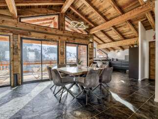 Experience luxurious mountain living in this stunning chalet featuring a spacious dining area with a modern chandelier and comfortable seating.