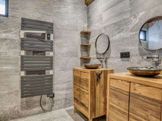 Experience rustic luxury in this stunning bathroom featuring exposed wooden beams and a natural stone tile finish.