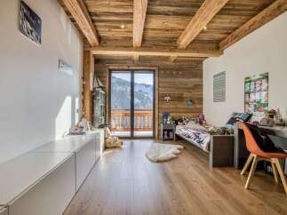 Experience mountain living in this charming alpine bedroom, featuring rustic wooden beams and paneling that create a cozy, natural ambiance.