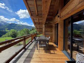 Experience breathtaking mountain views from this stunning wooden chalet's expansive balcony.