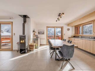 Experience cozy living in this charming dining and living area, featuring a modern wood-burning stove and a spacious wooden dining table perfect for family gatherings.