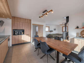 Experience modern alpine living in this beautifully appointed open-plan space, featuring a sleek kitchen with integrated appliances and ample wooden cabinetry.
