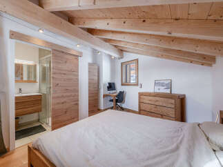 Experience rustic charm in this attic bedroom, featuring exposed wooden beams and a cozy ambiance.
