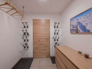 This ski room offers practical storage solutions with wall-mounted boot dryers and a convenient overhead rack for hangers.