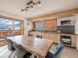 Experience breathtaking mountain views from this stunning dining area, featuring a large wooden table perfect for family gatherings.