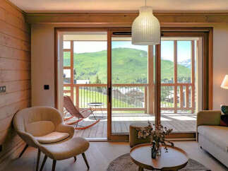 Experience breathtaking mountain views from this stunning living space, featuring a comfortable armchair and ottoman perfect for relaxation.