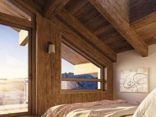 Experience breathtaking mountain views from this stunning bedroom, featuring a vaulted wooden ceiling and a large skylight that floods the space with natural light.