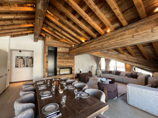Experience luxurious mountain living in this stunning chalet featuring a grand dining area with a rustic wooden table and elegant seating, perfect for hosting memorable gatherings.