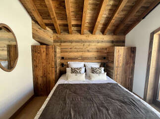 Experience rustic charm in this cozy bedroom featuring a beautifully paneled wooden headboard and ceiling.