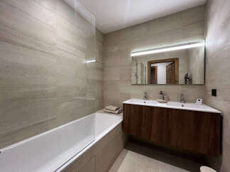 Experience modern luxury in this stunning bathroom featuring a sleek bathtub and a double vanity with a lighted mirror.