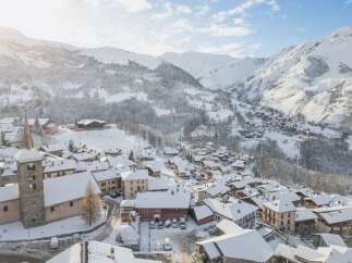 Experience the charm of a winter wonderland with this stunning aerial view of a snow-covered village nestled in the French Alps.