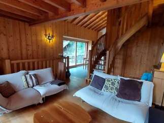 Experience rustic charm in this cozy living room featuring warm wood paneling and exposed beams.