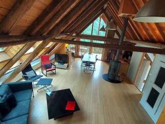 Experience rustic charm in this spacious loft living area, featuring exposed wooden beams and a vaulted ceiling.