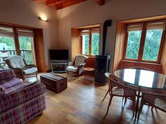 Experience cozy living in this charming mountain retreat, featuring a rustic plaid sofa and comfortable wicker armchairs perfect for relaxing.