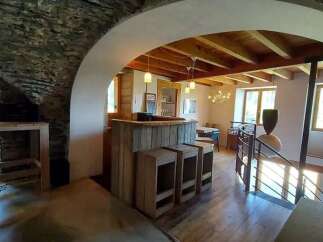 Discover this charming property featuring a rustic stone archway leading to a cozy bar area with wooden stools and a counter.