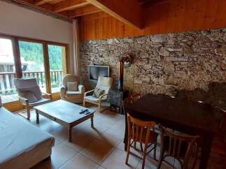 Experience rustic charm in this mountain retreat featuring a cozy living area with a stone accent wall and a wood-burning stove.