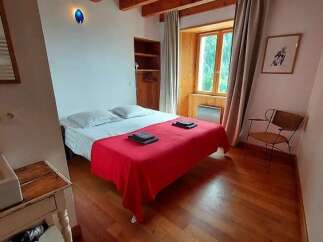 Experience cozy comfort in this charming bedroom, featuring a plush bed adorned with a vibrant red throw and crisp white linens.