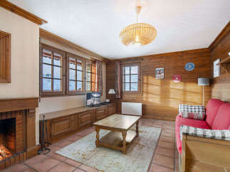 Experience cozy mountain living in this charming living room featuring a crackling fireplace and large windows with stunning alpine views.