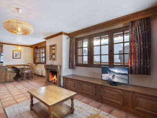 Experience cozy mountain living in this charming living area, featuring a crackling fireplace and large windows with stunning snowy views.