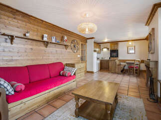 Experience cozy living in this charming mountain retreat, featuring a rustic wooden interior and a vibrant red sofa perfect for relaxation.