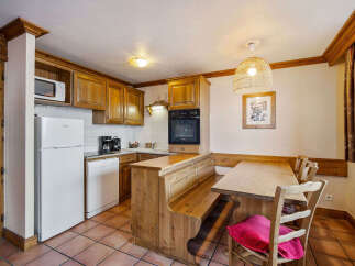 This charming kitchen and dining area features warm wooden cabinetry and a built-in banquette seating, perfect for cozy meals.