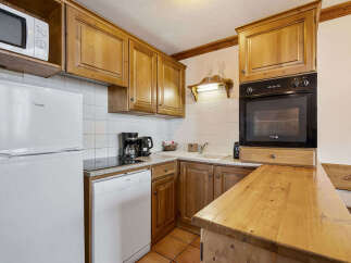 This charming kitchen features warm wooden cabinetry and a sleek black oven, perfect for preparing meals.