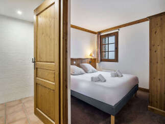 This charming bedroom features a comfortable double bed with crisp white linens and neatly rolled towels, perfect for a relaxing stay.