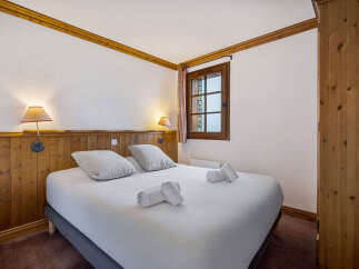 Experience cozy mountain living in this charming bedroom, featuring a comfortable bed adorned with plush pillows and neatly folded towels.