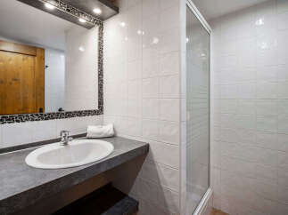 This modern bathroom features a sleek vanity with an integrated sink and a stylish mosaic-trimmed mirror.