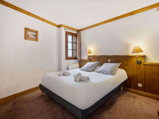 Experience cozy mountain living in this charming bedroom featuring a comfortable double bed adorned with plush pillows and neatly folded towels.