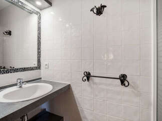 This bathroom features a sleek vanity with a modern sink and chrome faucet, complemented by a decorative mosaic mirror.