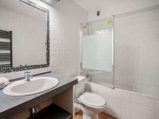 This bathroom features a modern vanity with a sleek countertop and a large mirror, perfect for your morning routine.
