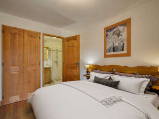 This charming bedroom features a cozy queen-size bed with crisp white linens and a decorative throw blanket.